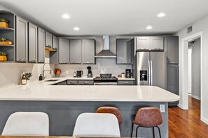 Una cocina moderna con armarios grises, una isla central y un refrigerador de acero inoxidable.
