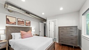 Un dormitorio con cama, mesitas de noche, cómoda y ventana.
