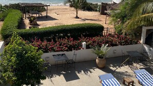 A beachside patio with lounge chairs, a table, and a small fire pit. - Bine Bassile (Guereo)