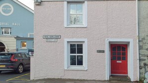 Un bâtiment avec une porte rouge, une fenêtre et une enseigne indiquant « Heol Gorllewin West St. »