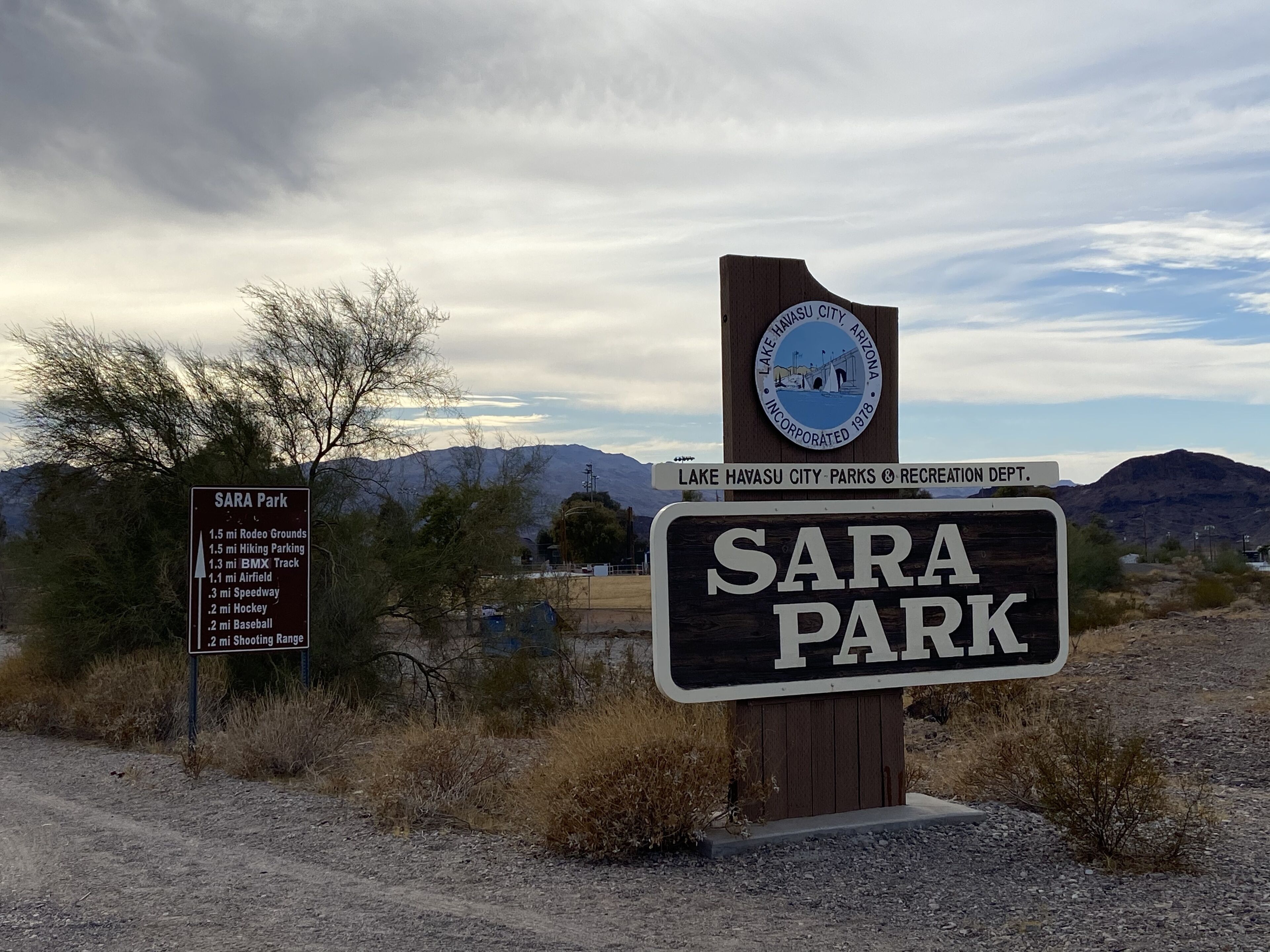 Un panneau indiquant le parc Sara, avec une liste des équipements disponibles, notamment une piste de BMX et un stand de tir.