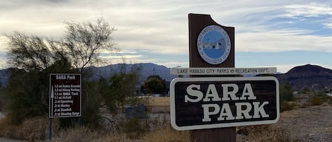 Un panneau indiquant le parc Sara, avec une liste des équipements disponibles, notamment une piste de BMX et un stand de tir.