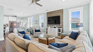 A living room with a sofa, a coffee table, a television, and a ceiling fan.