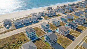 A coastal residential area with houses, a beach, and a clear sky.