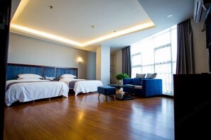 Een hotelkamer met twee bedden, een bank, een kleintje tafel en een groot raam.