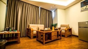 Un salon comprenant un canapé, des fauteuils, une table basse, un téléviseur et un réfrigérateur.