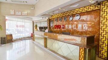 A hotel reception area with a marble counter, a reception desk, and a window with blinds.