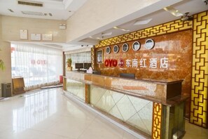 A hotel reception area with a marble counter, a reception desk, and a window with blinds.
