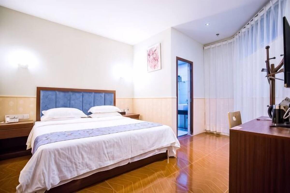 Une chambre d’hôtel avec un lit, des tables de chevet, un bureau et une chaise.