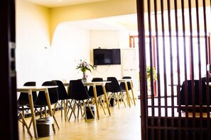 Une salle de conférence avec une longue table, des chaises, un téléviseur et une plante.