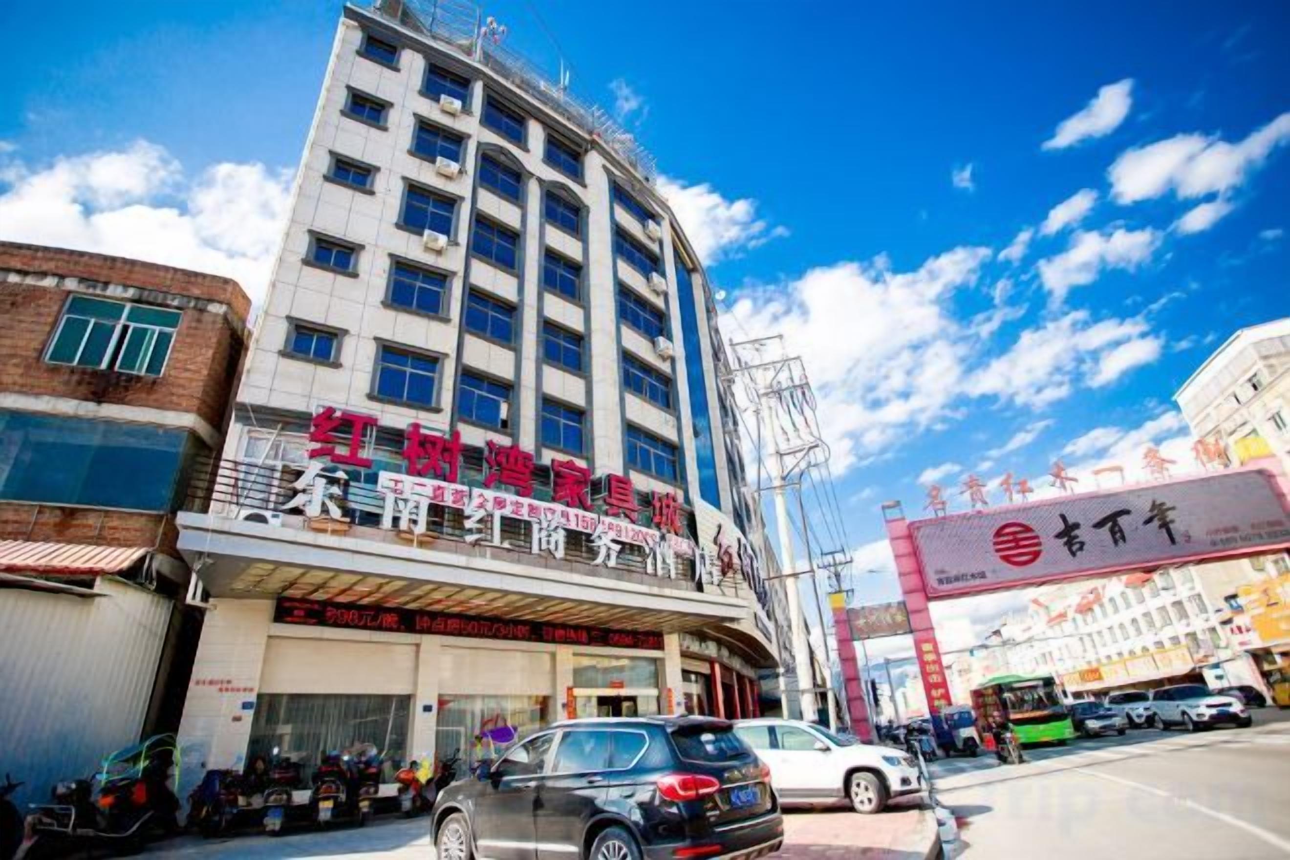 Un edificio de varios pisos con un local comercial en la planta baja, cielo despejado y una calle al frente.