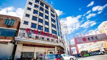 Un edificio de varios pisos con un local comercial en la planta baja, cielo despejado y una calle al frente.