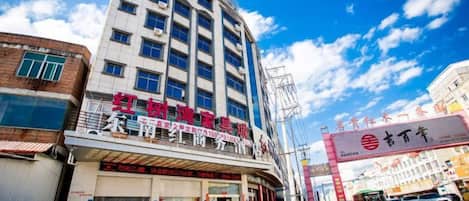 Un edificio de varios pisos con un local comercial en la planta baja, cielo despejado y una calle al frente.