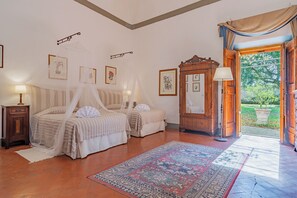 Un dormitorio con dos camas, un espejo grande y vistas al jardín a través de una puerta abierta.