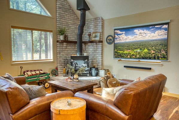 A cozy living room with leather sofas, a brick fireplace, and a large window with a scenic view.