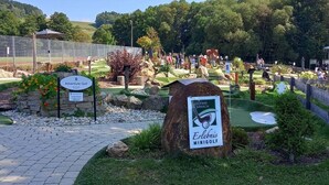 Un campo da golf con un cartello per Adventure Golf e un altro per Erlebnis Minigolf.