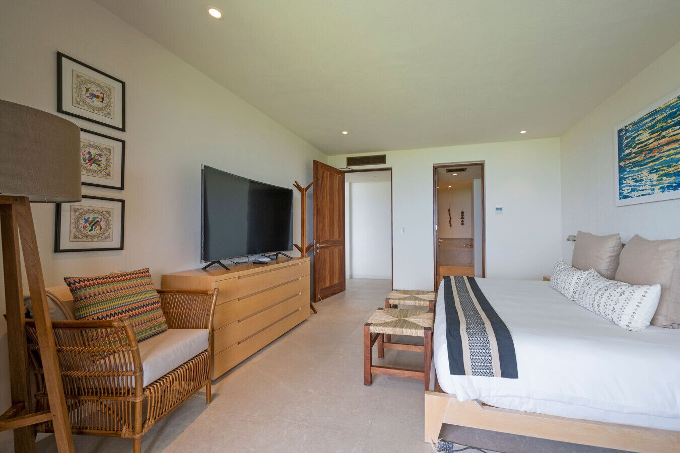 Een moderne hotelkamer met een groot bed, een televisie, een houten dressoir en een zithoek met een stoel en een tafeltje.