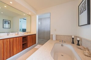 Une salle de bain moderne avec une grande baignoire, un meuble-lavabo en bois et un grand miroir.