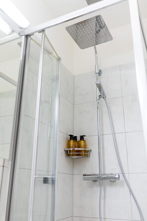 Enjoy a refreshing shower experience with a glass-enclosed shower stall and convenient handheld showerhead.