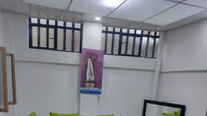 Ein modernes Wohnzimmer mit einem grauen Sofa, grünen Kissen, einem Holztisch und einem gemusterten Sessel.