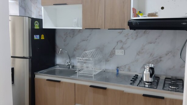 Eine moderne Küche mit Holzausstattung, einem Edelstahlkühlschrank, einem Gasherd und einer Marmor-Spritzschutzwand.