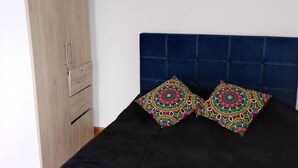 Ein Schlafzimmer mit einem Holzkleiderschrank, einem Bett mit dunkler Kopfteil und einem dekorativen Vogelkäfig an der Wand.