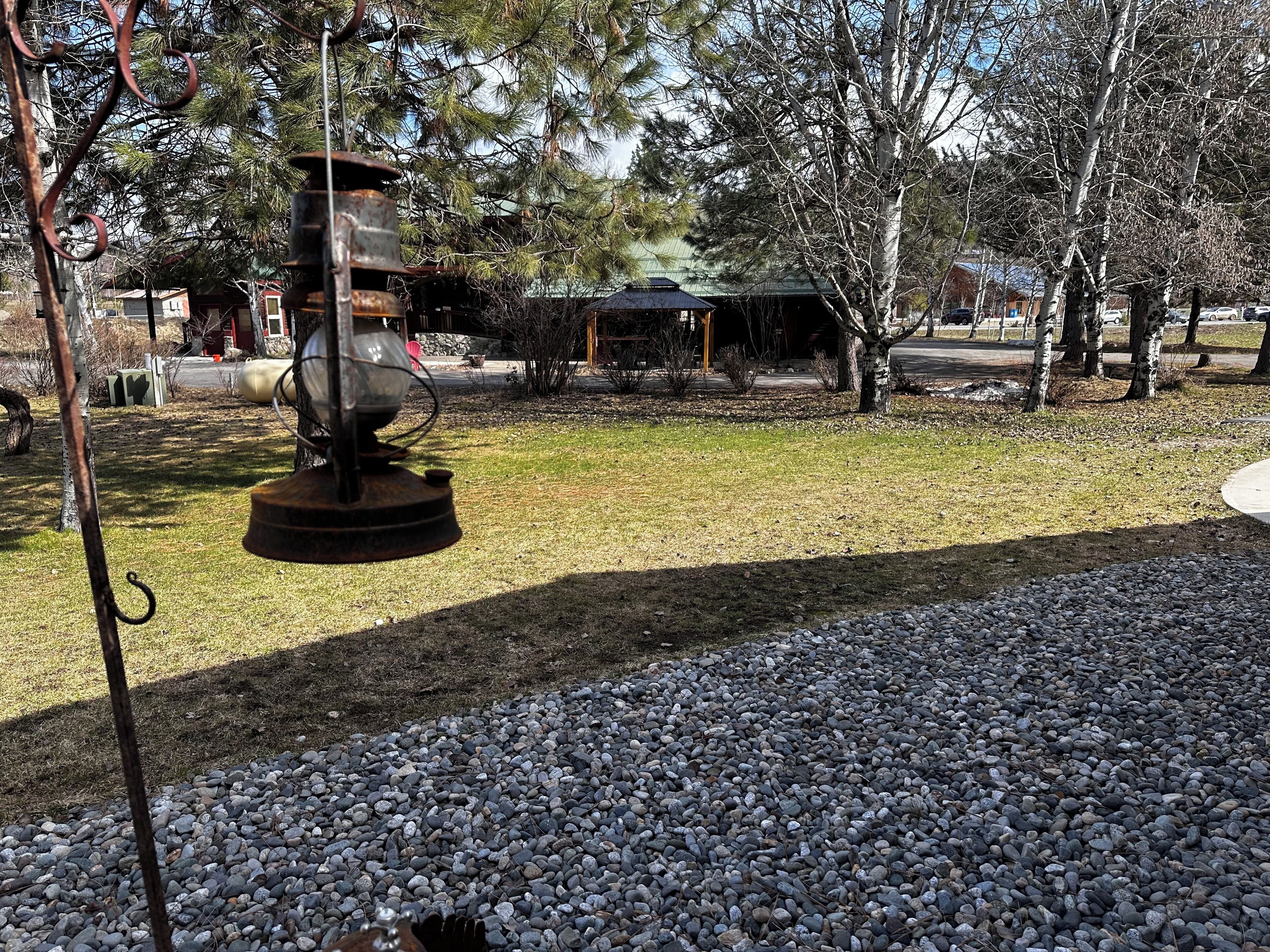 A rustic outdoor area with a metal sculpture, a gravel path, and trees.