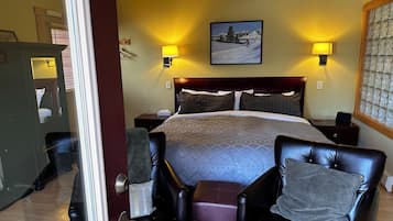 Een hotelkamer met een groot bed, twee bedlampen, een plafondventilator, een ingelijst schilderij aan de muur en uitzicht buiten door een raam.