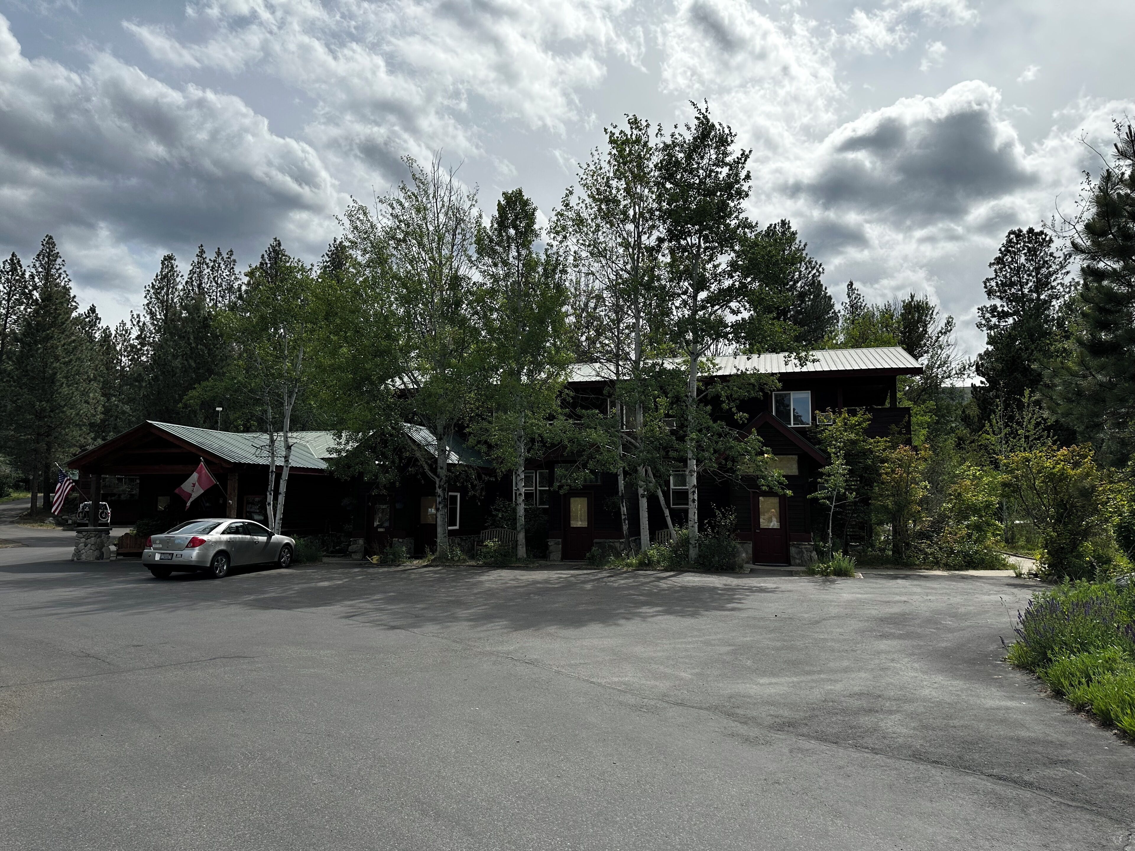 A lodge with a covered parking area, surrounded by trees.