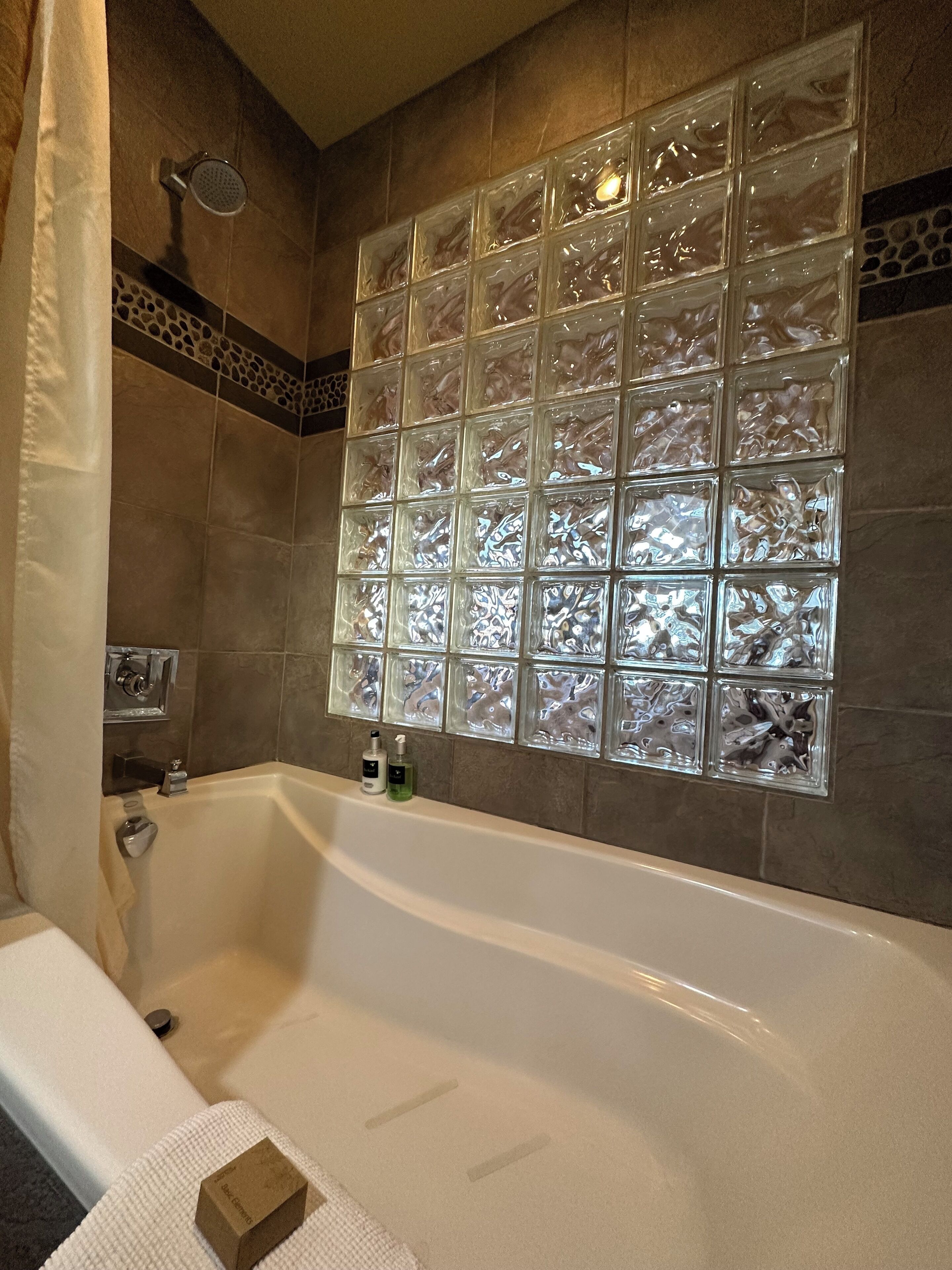 A bathroom with a bathtub, a glass shower enclosure, and a tiled wall with a decorative pattern.