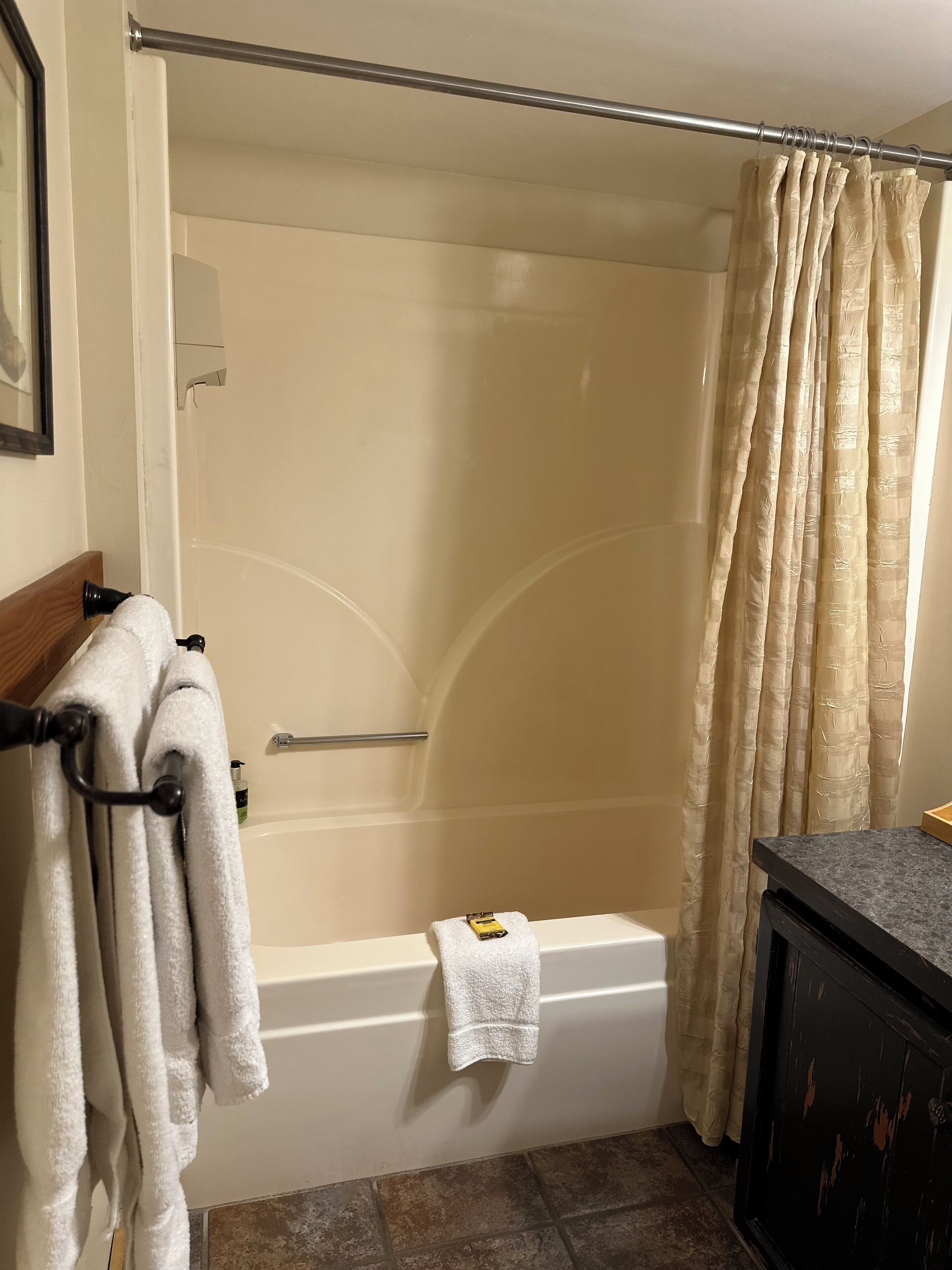 Un baño con bañera, cortina de ducha y toallero con toallas.