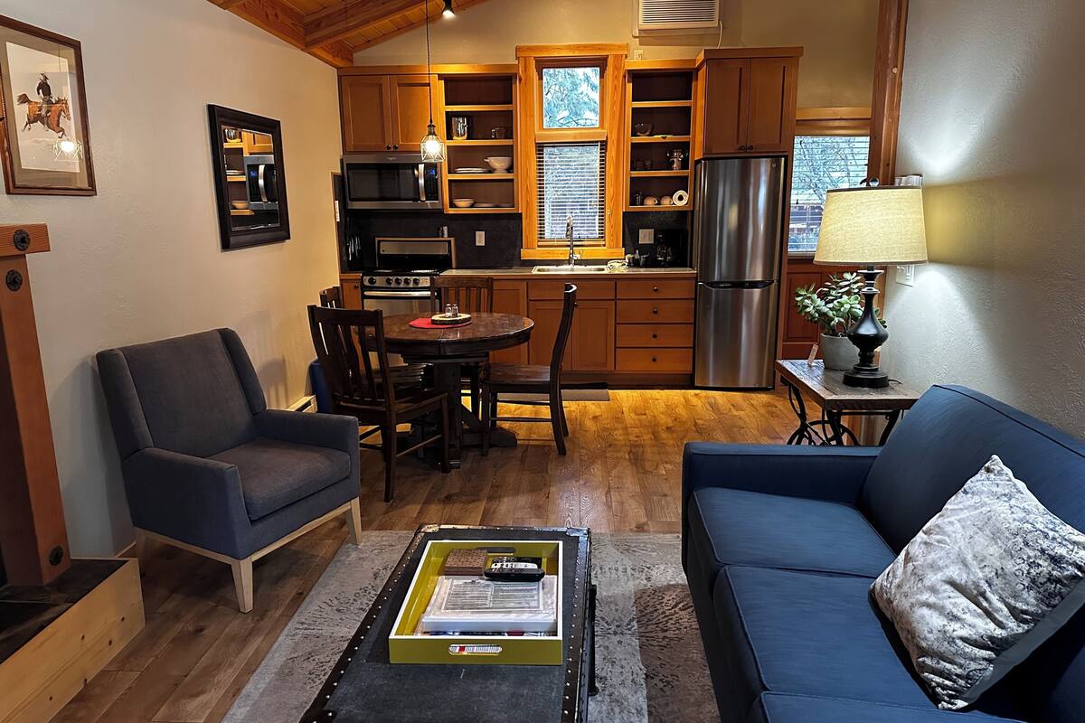 A cozy living room with a blue sofa, a coffee table, and a dining area with wooden chairs and a small table.