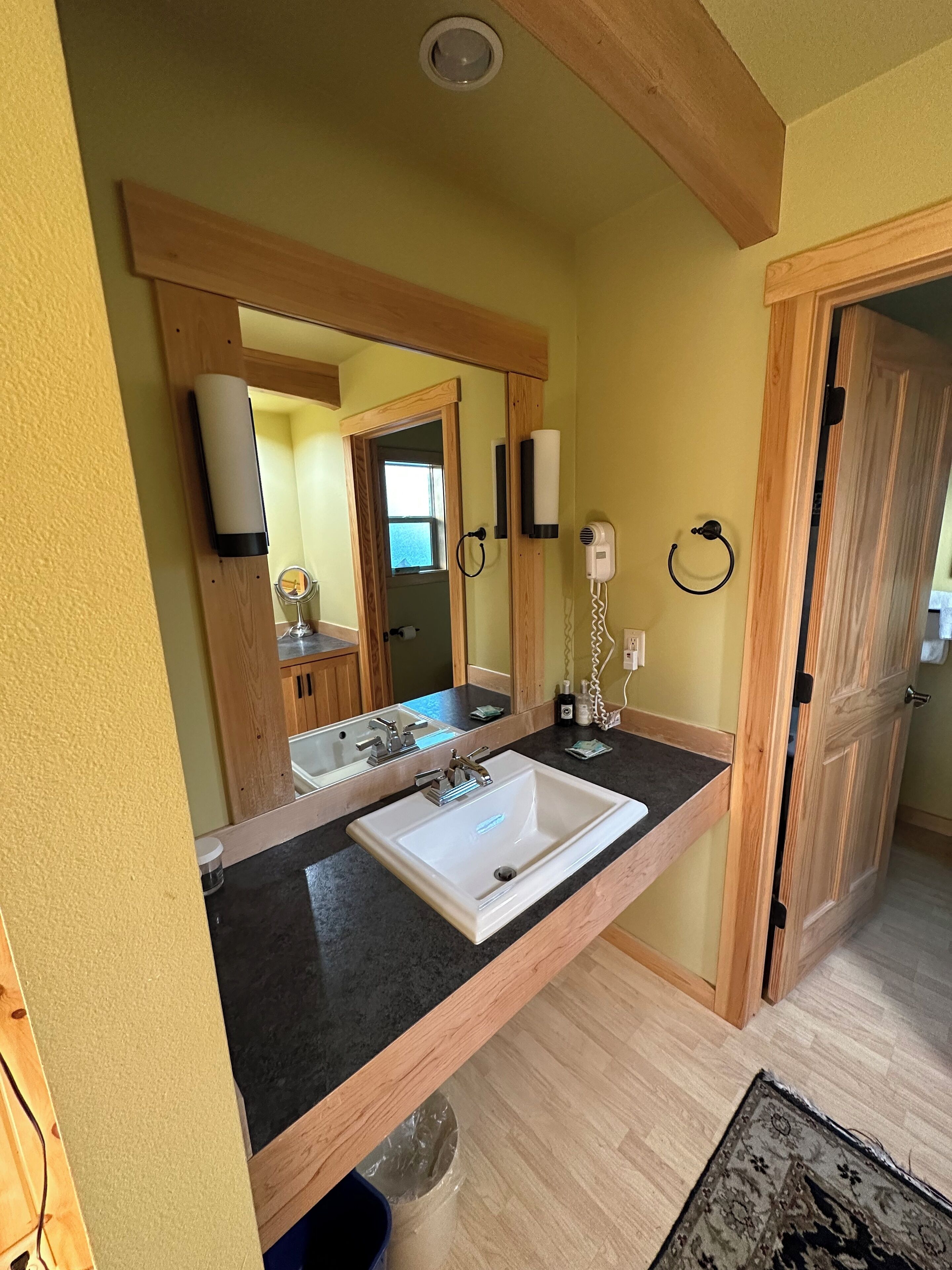 A bathroom with a large mirror, a sink, and a hairdryer.