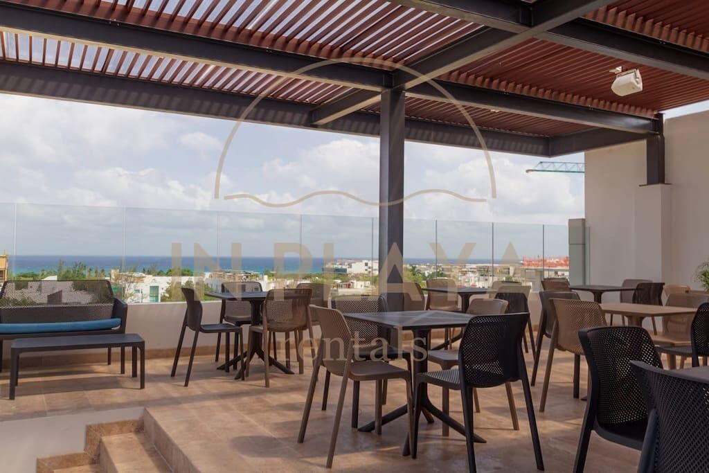 Eine Dachterrasse mit Sitzgelegenheiten im Freien und Blick auf Stadt und Meer.
