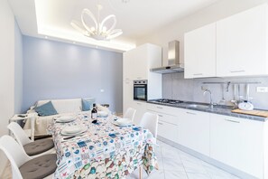 A modern kitchen with white cabinets, a built-in oven, and a stainless steel range hood. - Bedo House Beach Front (Follonica)