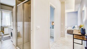 A modern bathroom with a glass shower enclosure, a built-in washing machine, and a toilet. - Bedo House - Beachfront Sea View Apartment in Follonica (Follonica)