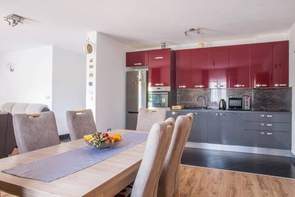 Una cucina moderna con pensili rossi, un frigorifero in acciaio inossidabile e un forno a microonde.