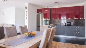 Una cocina moderna con armarios rojos, un refrigerador de acero inoxidable y un microondas.