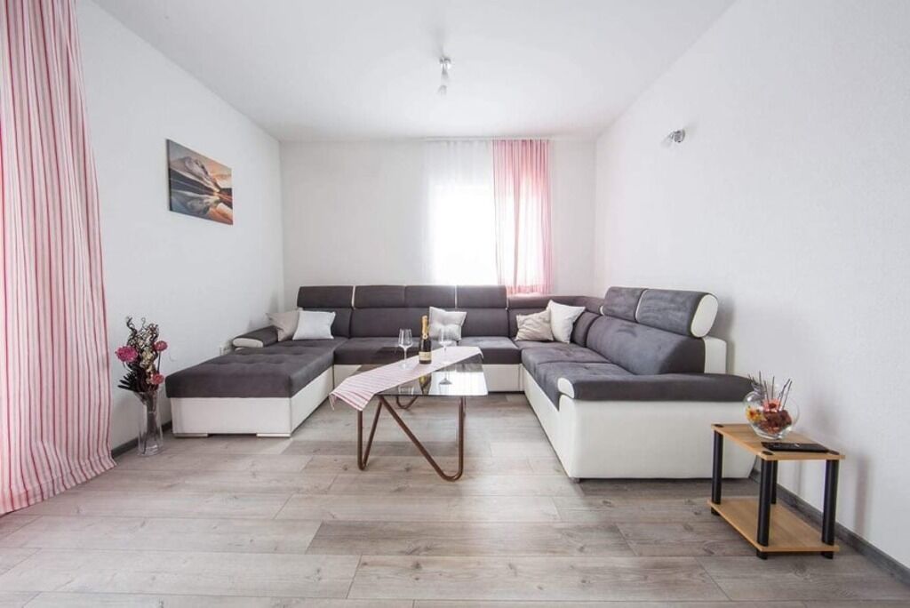 Uma sala de estar moderna com um sofá seccional, uma mesinha de centro e uma mesa lateral com um vaso.