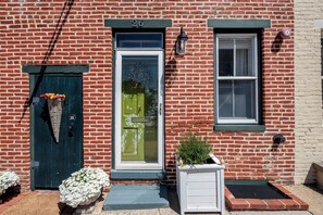 A red brick building with a green door, a window, and a white mailbox. - Garden Retreat on Carroll Creek + Free Parking (Frederick)