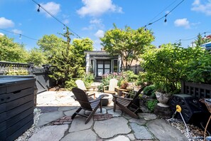 Une terrasse avec des meubles d’extérieur, un barbecue et un chemin en pierre.