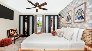 A bedroom with a bed, a ceiling fan, a TV, and a window with curtains.