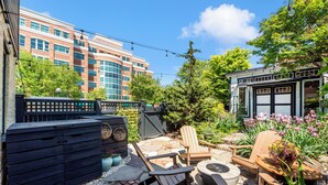 A patio area with outdoor seating, a storage unit, and a building in the background.