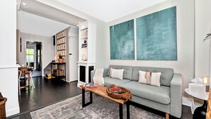 A modern living room with a grey sofa, a wooden coffee table, and a bookshelf.