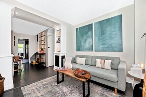 A modern living room with a grey sofa, a wooden coffee table, and a bookshelf.