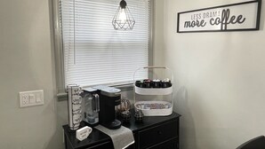 A kitchenette with a coffee maker, a kettle, and a mug on a black countertop. There's a window with blinds and a sign on the wall that says "LES DRAMA more coffee". - 1st Floor Completely Remodeled, Pets Welcome!!! King & Queen Beds, W/D in Unit., (Monroe)