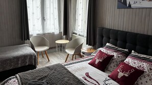 Habitación de hotel con cama, dos sillones, una mesita y ventana con cortinas.