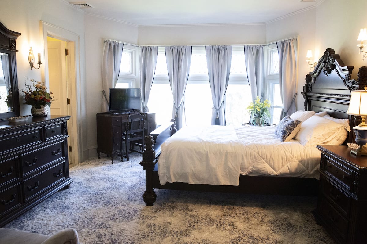 A bedroom with a large bed, a dresser, a desk, and a television.