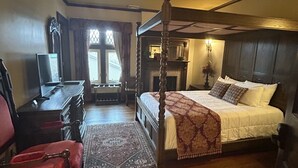 Una cama con dosel tradicional, cabecera de madera, un escritorio con silla y una chimenea.
