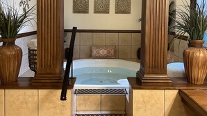 Un cuarto de spa con bañera de hidromasaje, columnas de madera y paneles decorativos.